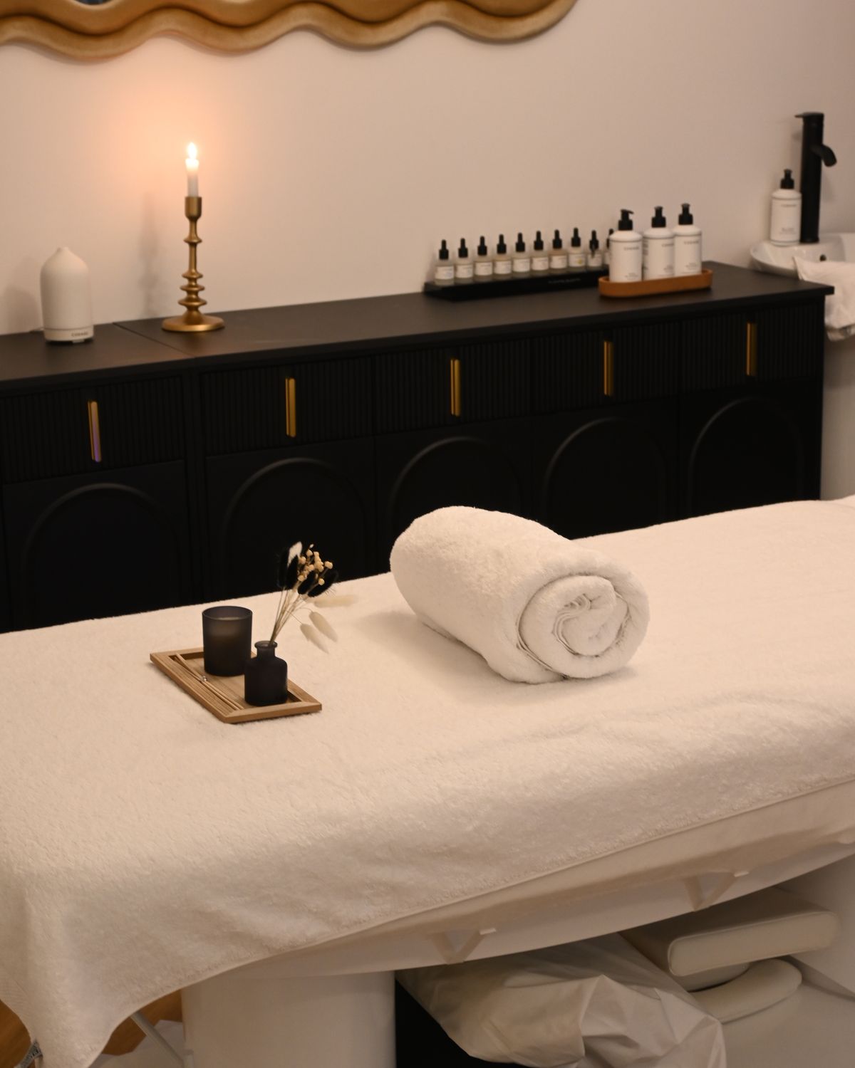 Salle de massage apaisante avec serviette roulée, bougie et huiles essentielles
